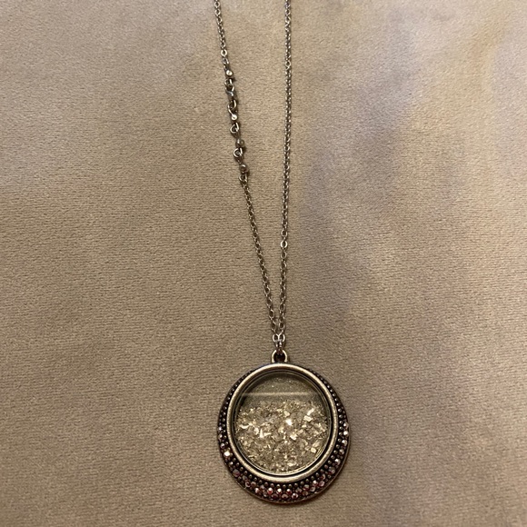 Necklace with silver colored medallion and silver glitter.